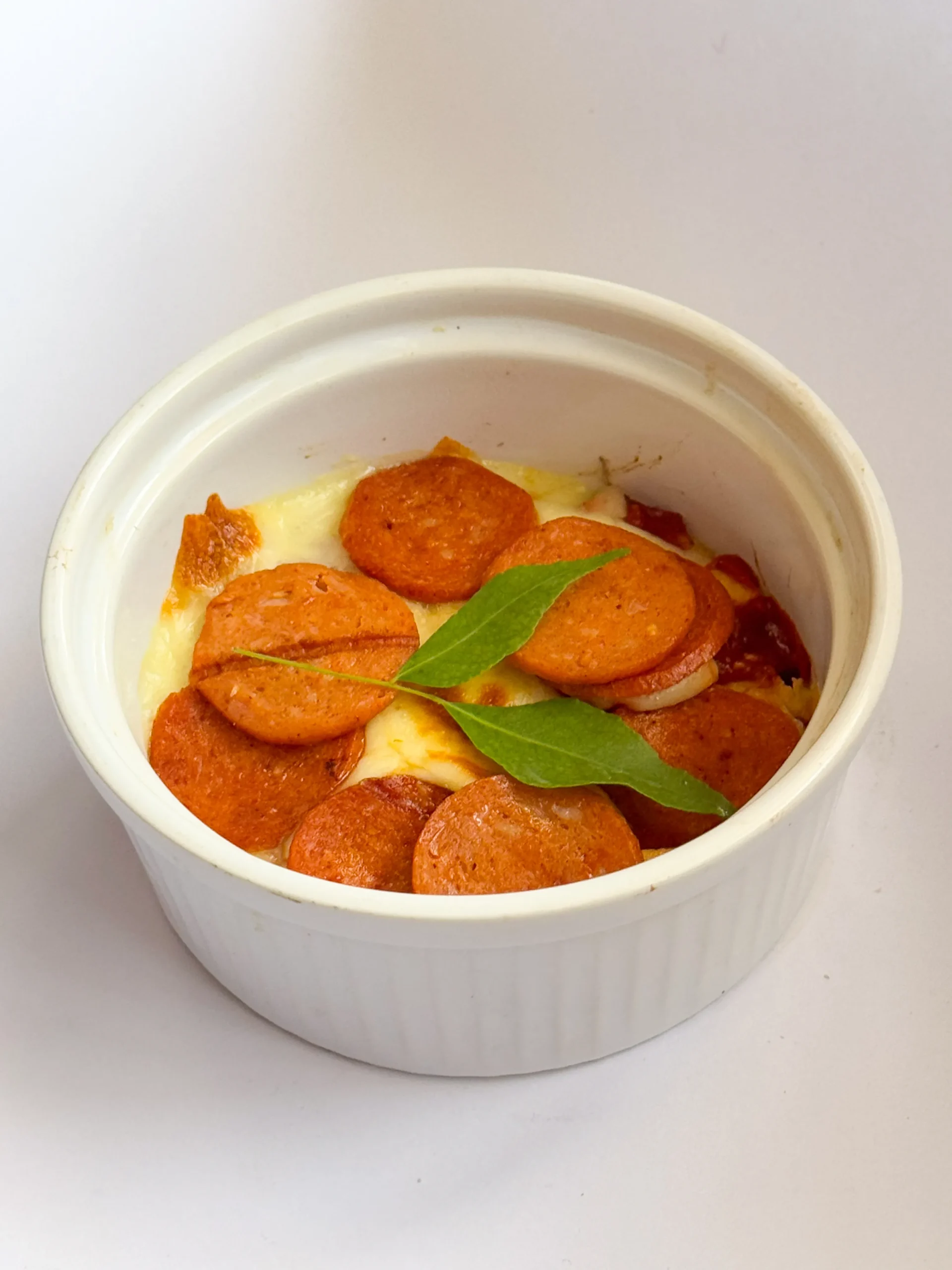 Pizza bowl topped with pepperoni slices and basil leaves.